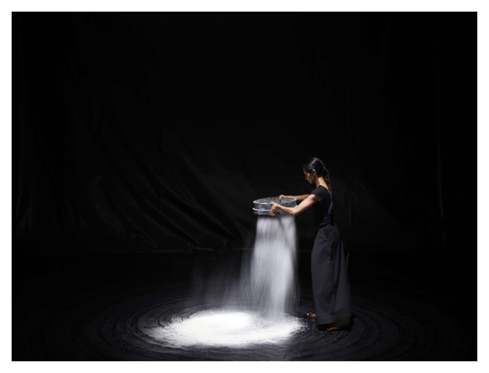 La danseuse Shantala Shivalingappa passe des cendres au tamis pour dessiner un motif au sol. 