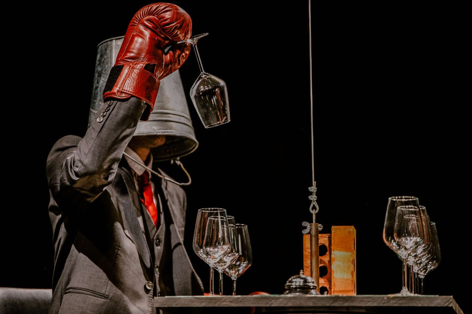 Le héros manipule des verres à pied muni de gants de boxe et d'un sot sur la tête