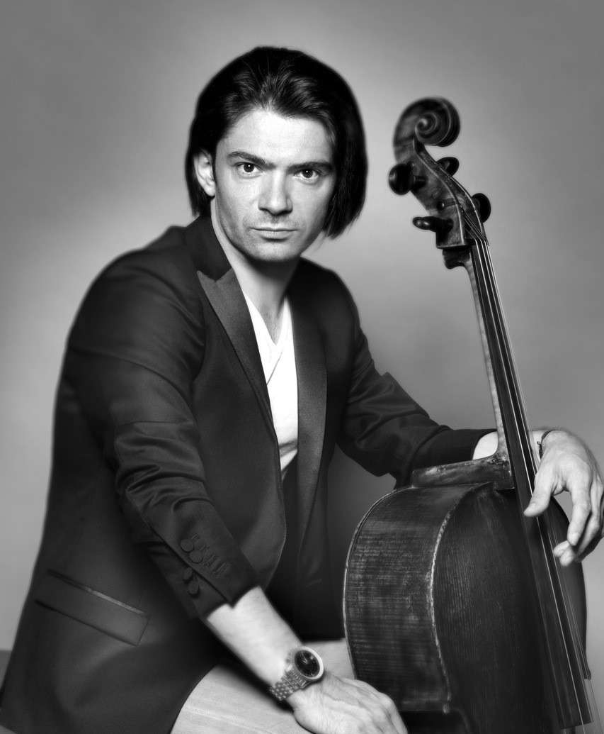 Portrait noir et blanc de Gautier Capuçon sortant de chez le coiffeur et posant avec son violoncelle. 