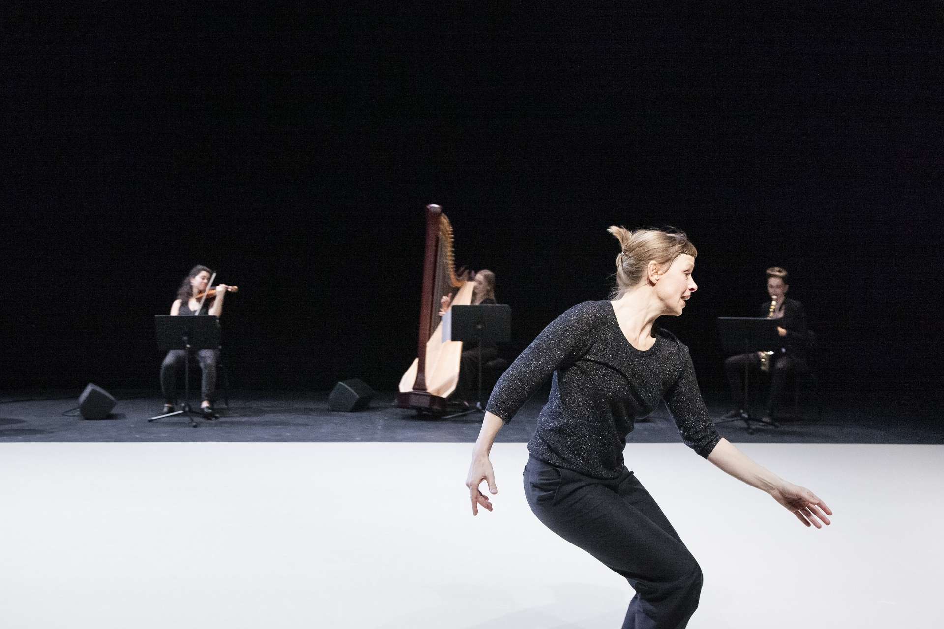 Samantha van Wissen, danseuse et interprète de Giselle..., effectue un mouvement dansé en bord de scène alors que trois musiciennes jouent en fond de scène. 