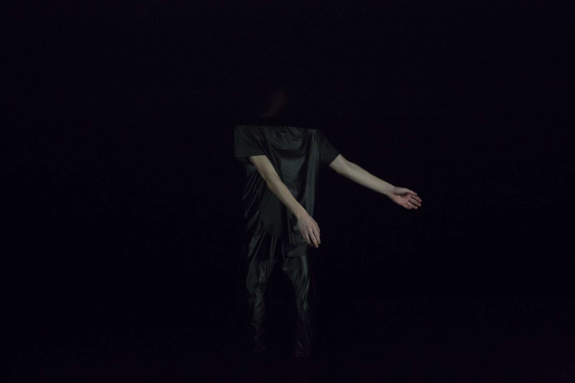 Tenue noire pour le danseur de Larsen C et fond noir, cela laisse seulement percevoir ses mains et leur mouvement. 
