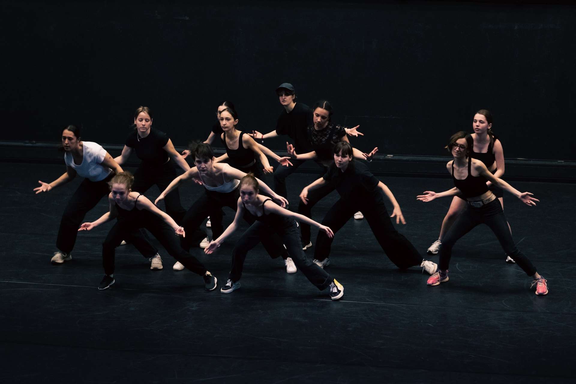 Sur scène, dans la pénombre, ballet d'interprètes du projet Sources de Simon Dimouro. 