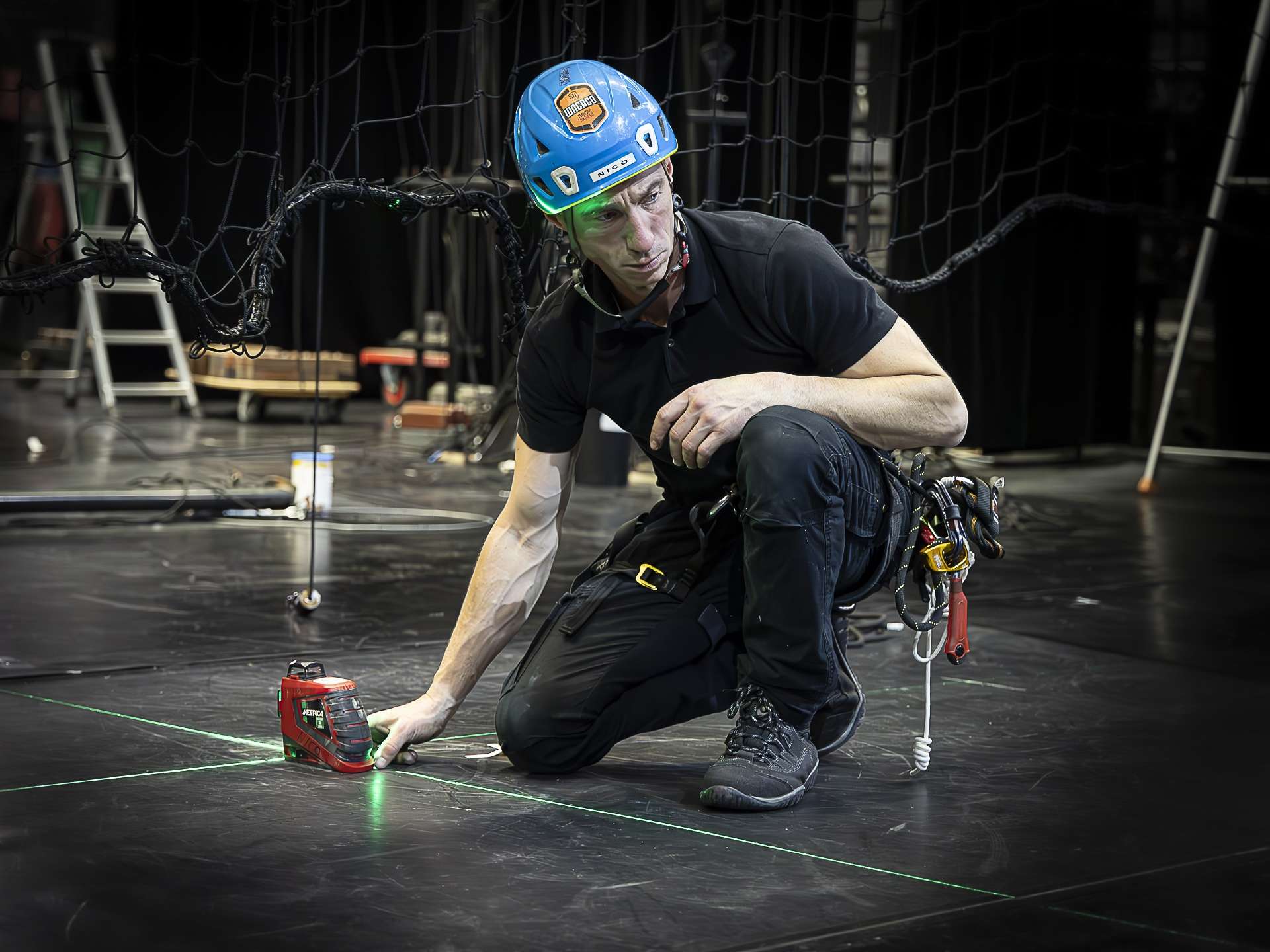 Technicien prenant des cotes d'axes sur le plateau pour placer les éléments de décors.