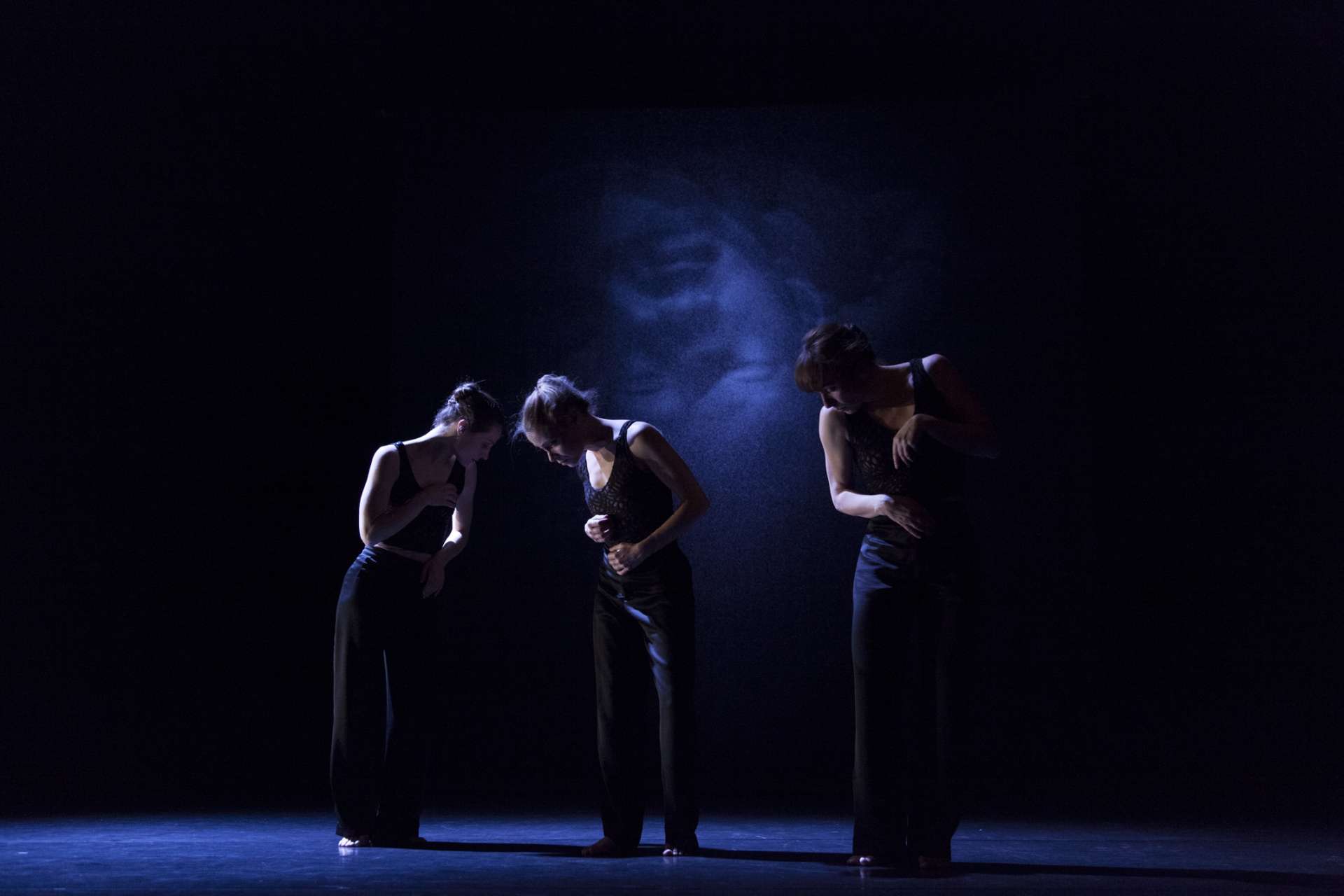 Dans la pénombre de la scène, trois silhouettes de femme dansent. Parmi elles, la chorégraphe, Anne-Sophie Lancelin. 