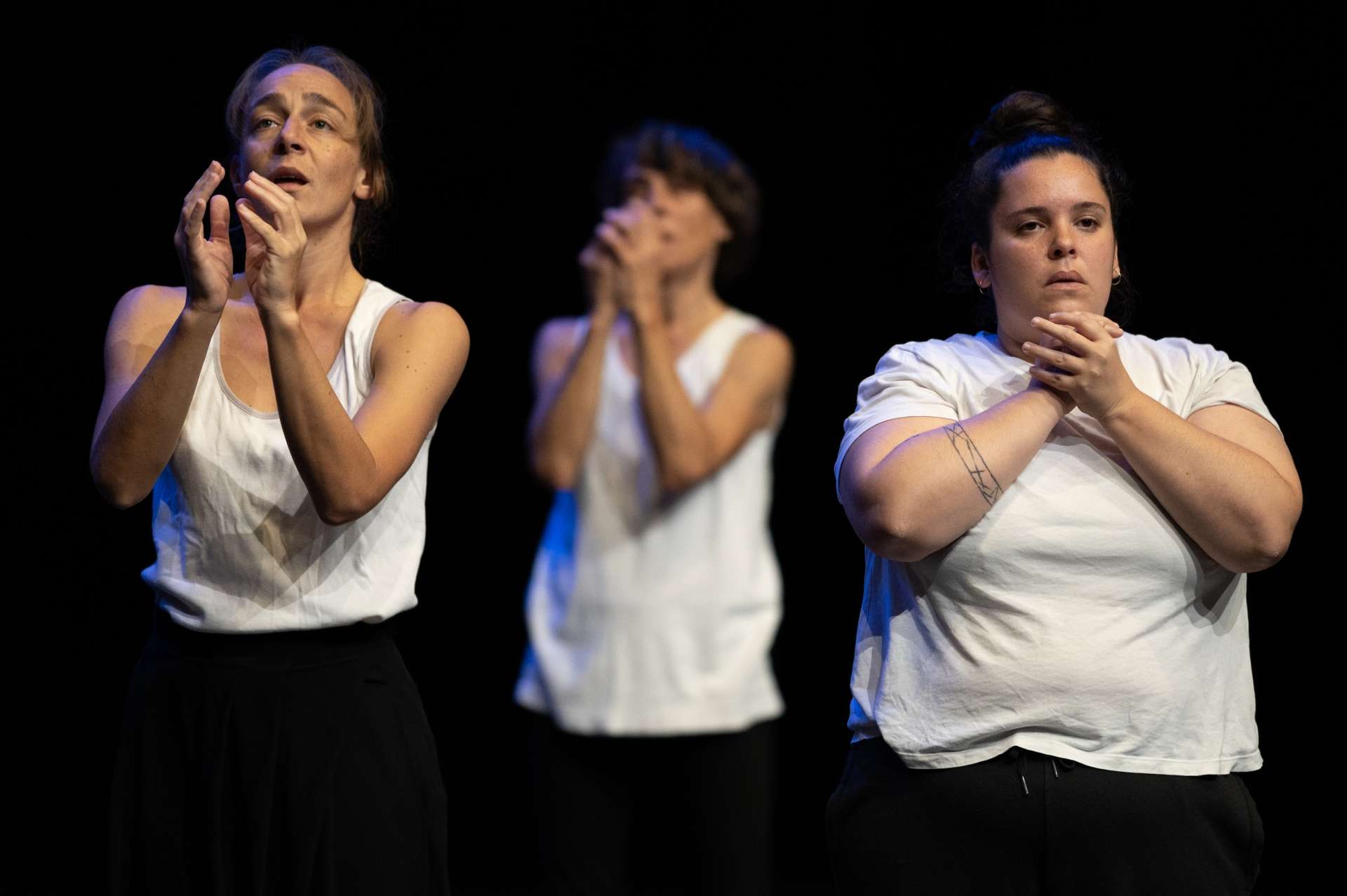 Sur scène, vêtus d'un débardeur blanc, trois interprètes de la pièce Abwarten expriment chacun une émotion. 