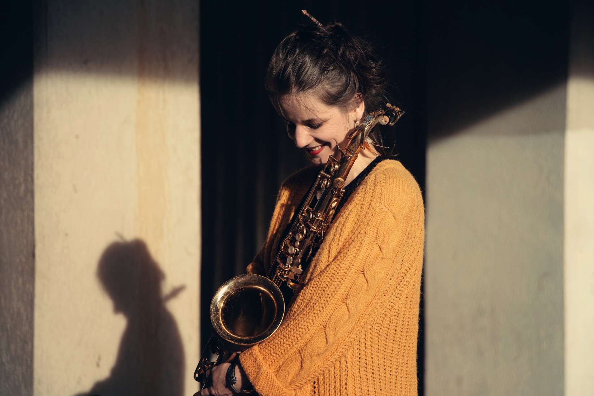 Portrait ensoleillée de Camille Maussion regardant son saxophone.