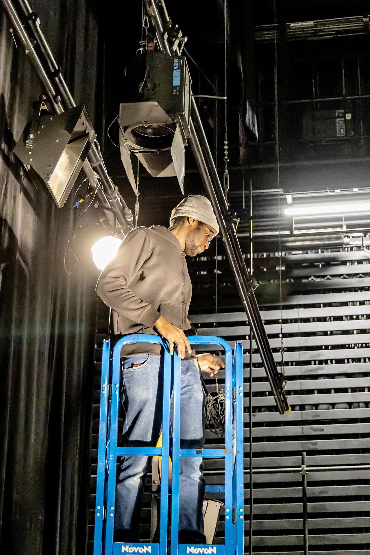 Technicien dans une nacelle réglant les volets d'un projecteur.