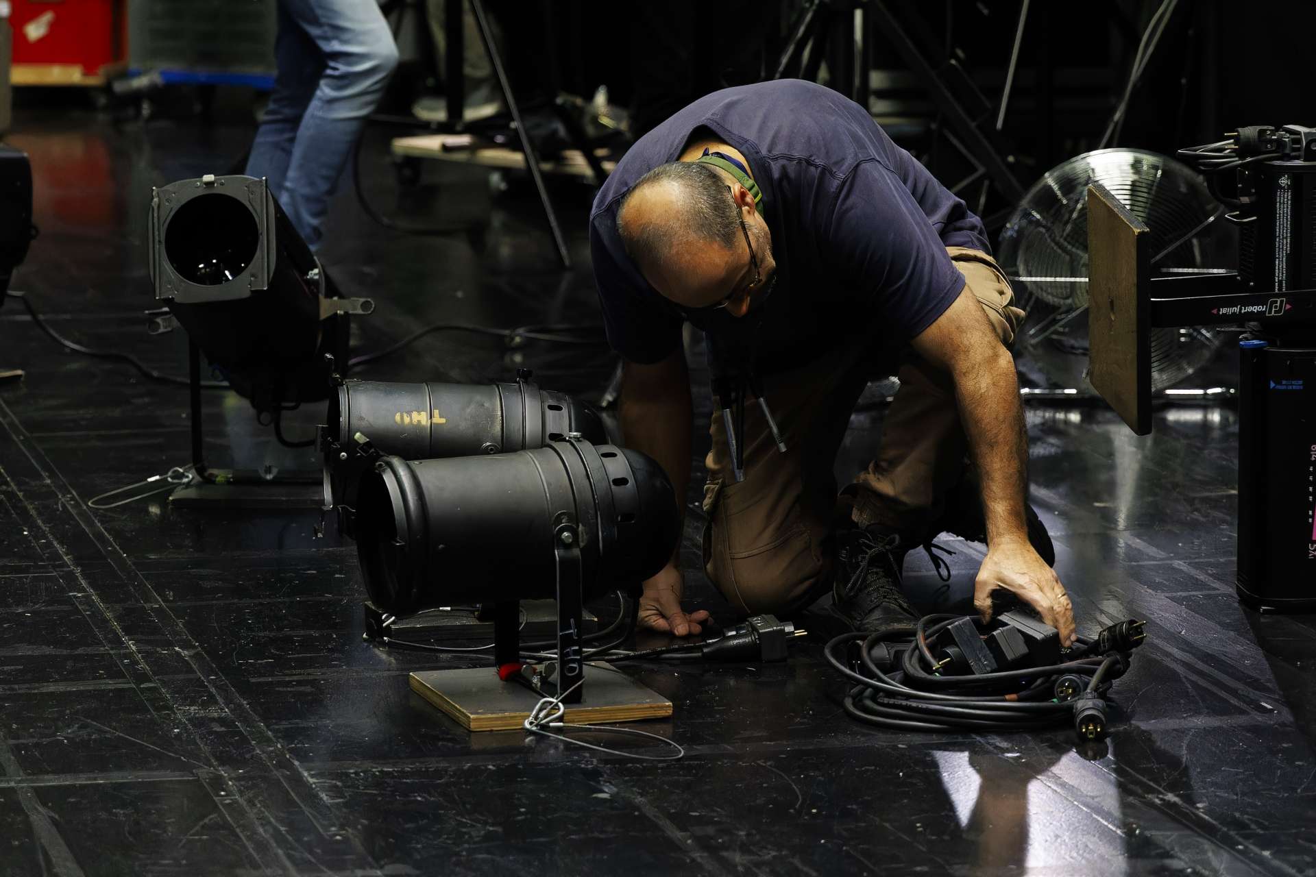 Technicien lumière branchant des projecteurs sur le plateau.