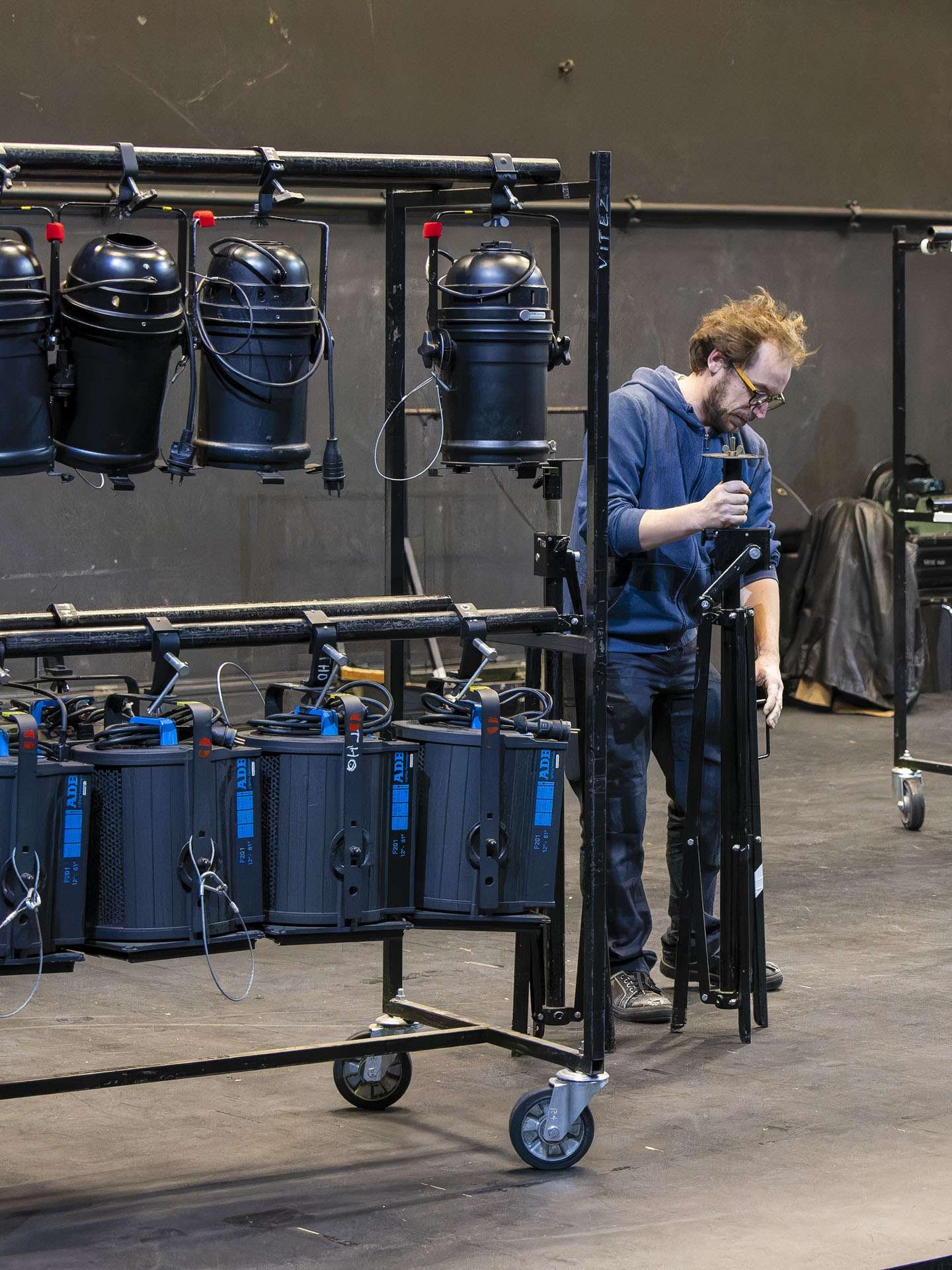 Technicien lumière installant un pied de projecteur.
