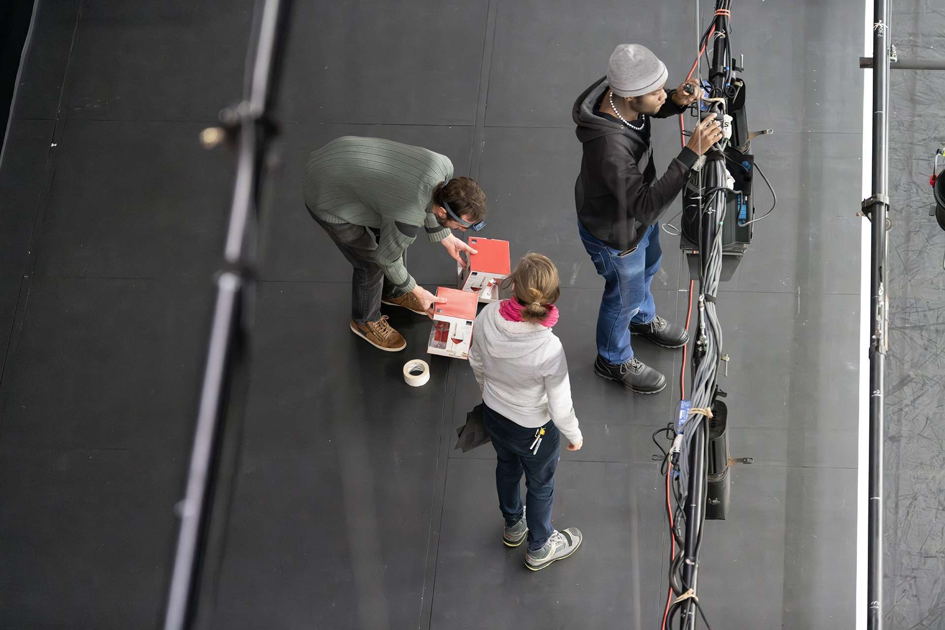 Techniciens et technicienne en train d'installer du décor et des projecteurs.
