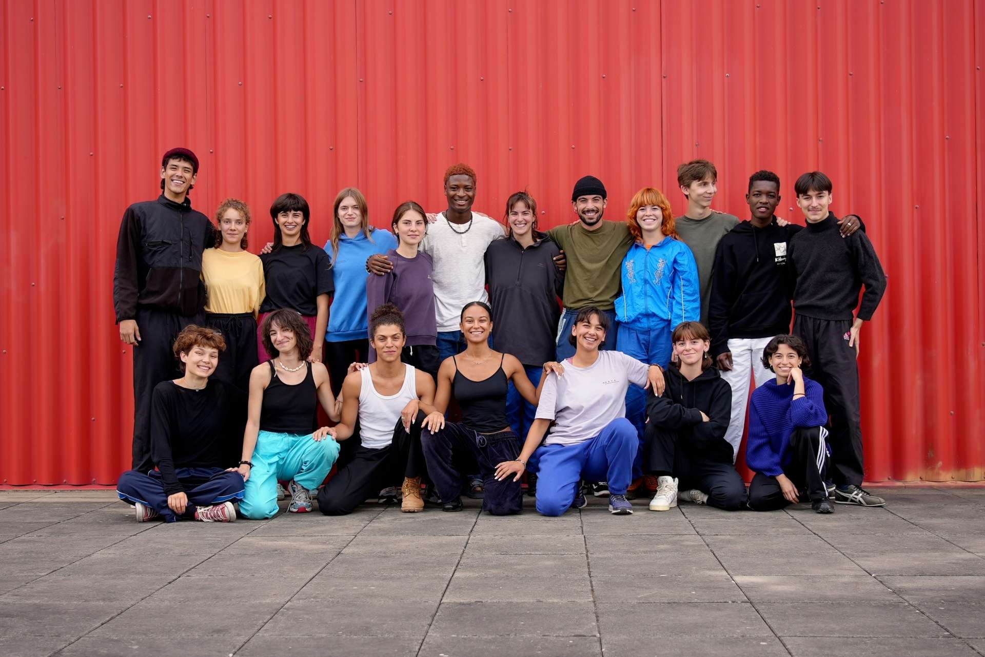 Dix-neuf interprètes de l'école supérieure du Cndc-Angers posent en mode photo de classe devant un conteneur rouge. 