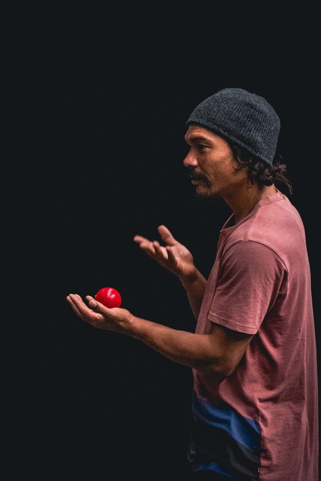 Un circassien qui explique les consignes de l'atelier jonglage, avec une balle rouge dans la main. 
