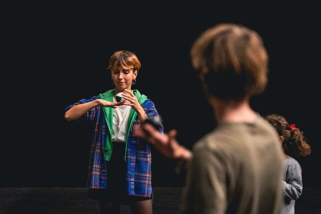Une jeune femme debout jonglant avec une balle, en équilibre sur sa main, concentrée sur son mouvement.