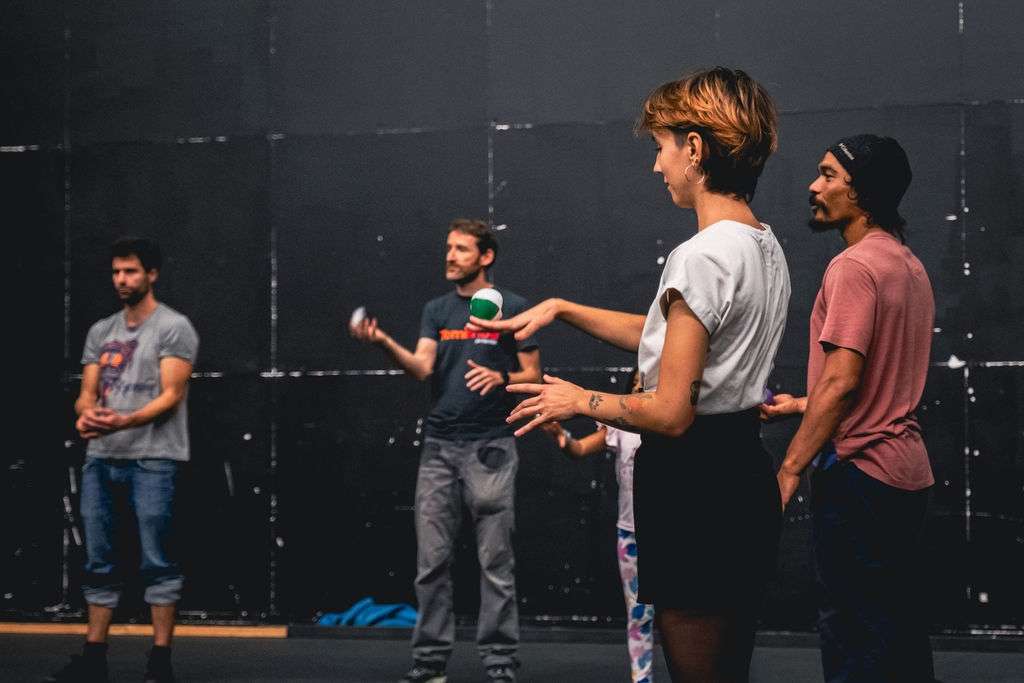Des adultes debout en cercle lors d'un atelier, certains jonglant avec des balles, concentrés sur leurs mouvements.