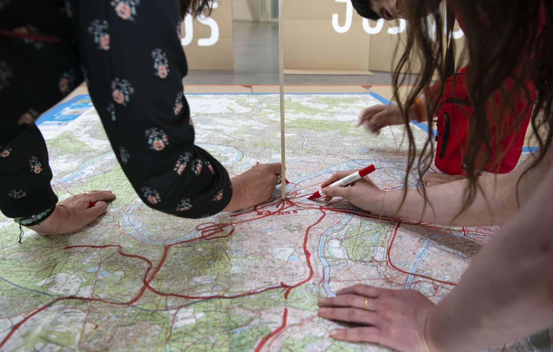 Une carte est installée au sol et deux personnes dont l'on voit seulement les mains dessinent. 
