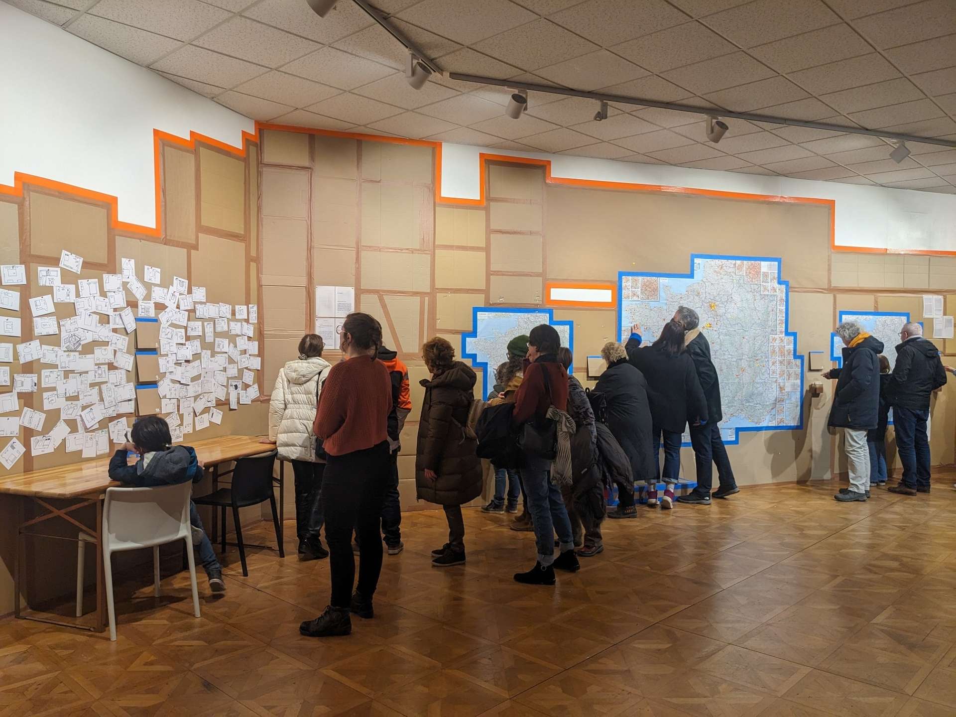 La Galerie du Théâtre d'Orléans avec les murs recouverts de cartons et du public qui écrit sur les murs. 