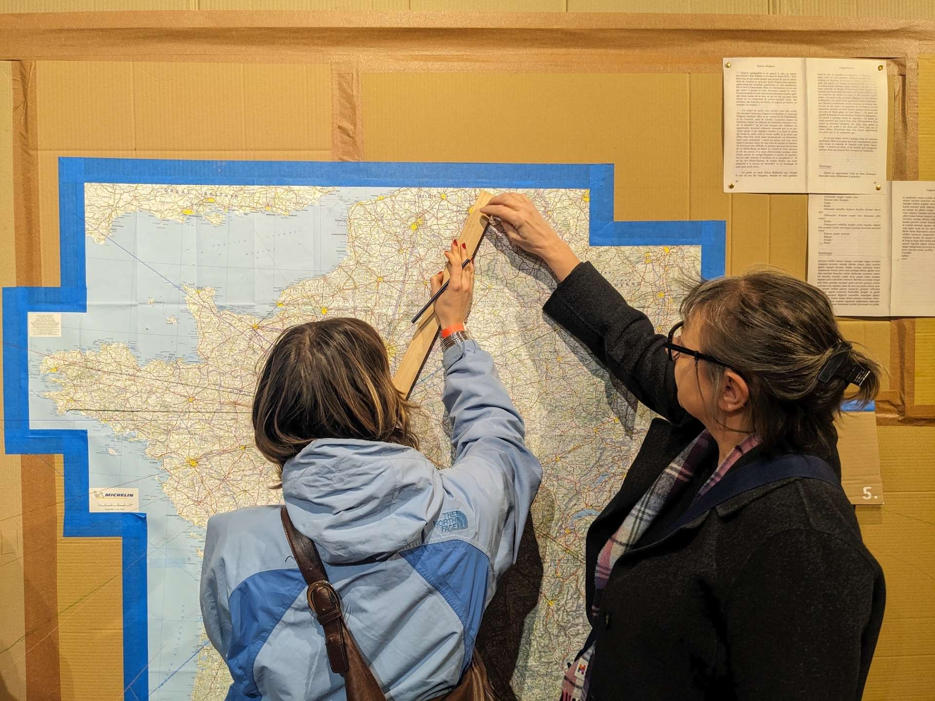 Deux femmes sont en train de faire des traits sur une carte. 