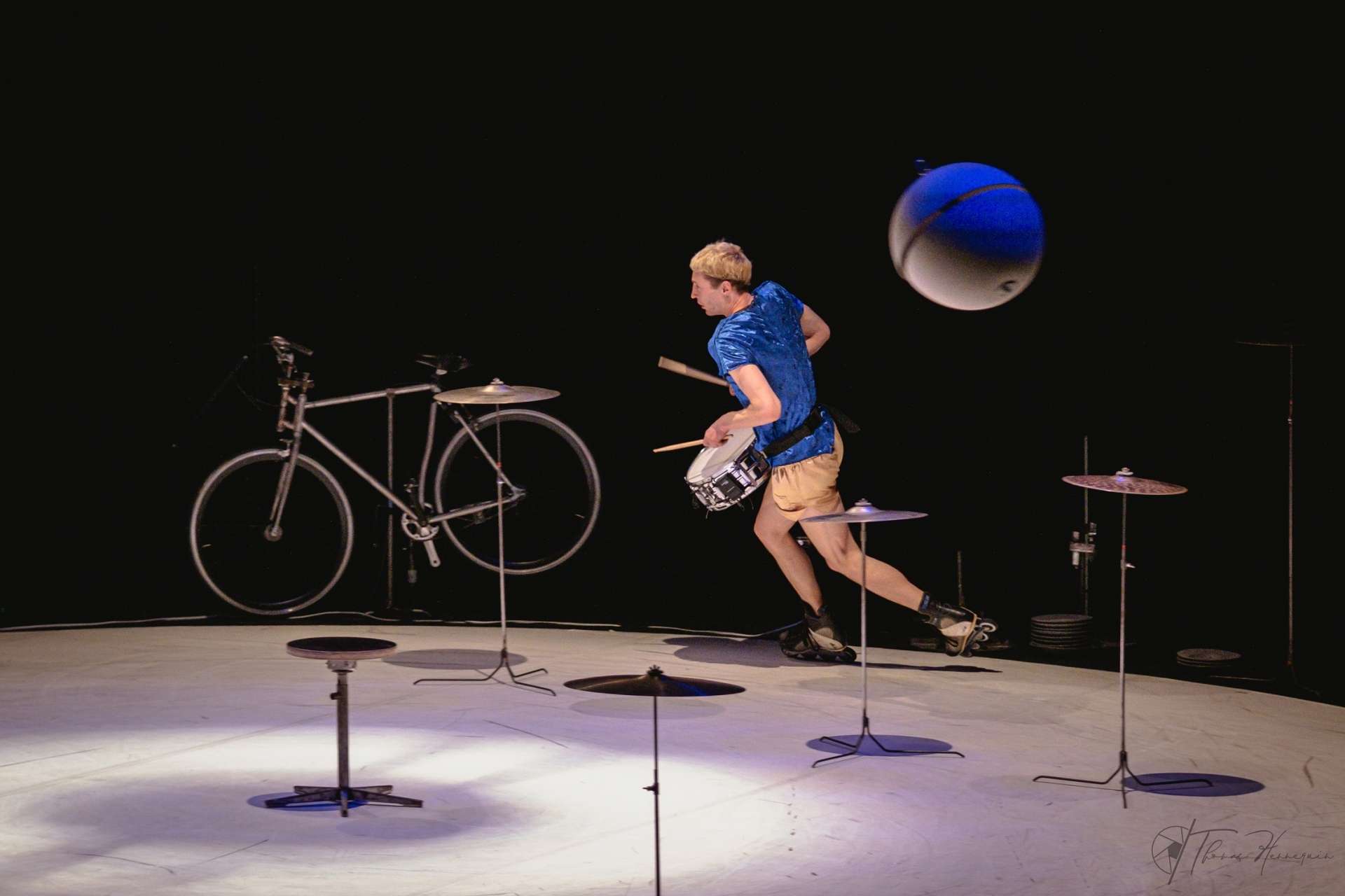 Quelques cymbales, une piste blanche, un vélo, Julian Vogel qui fait du tambour en roller et une grosse boule suspendue qui le poursuit. 