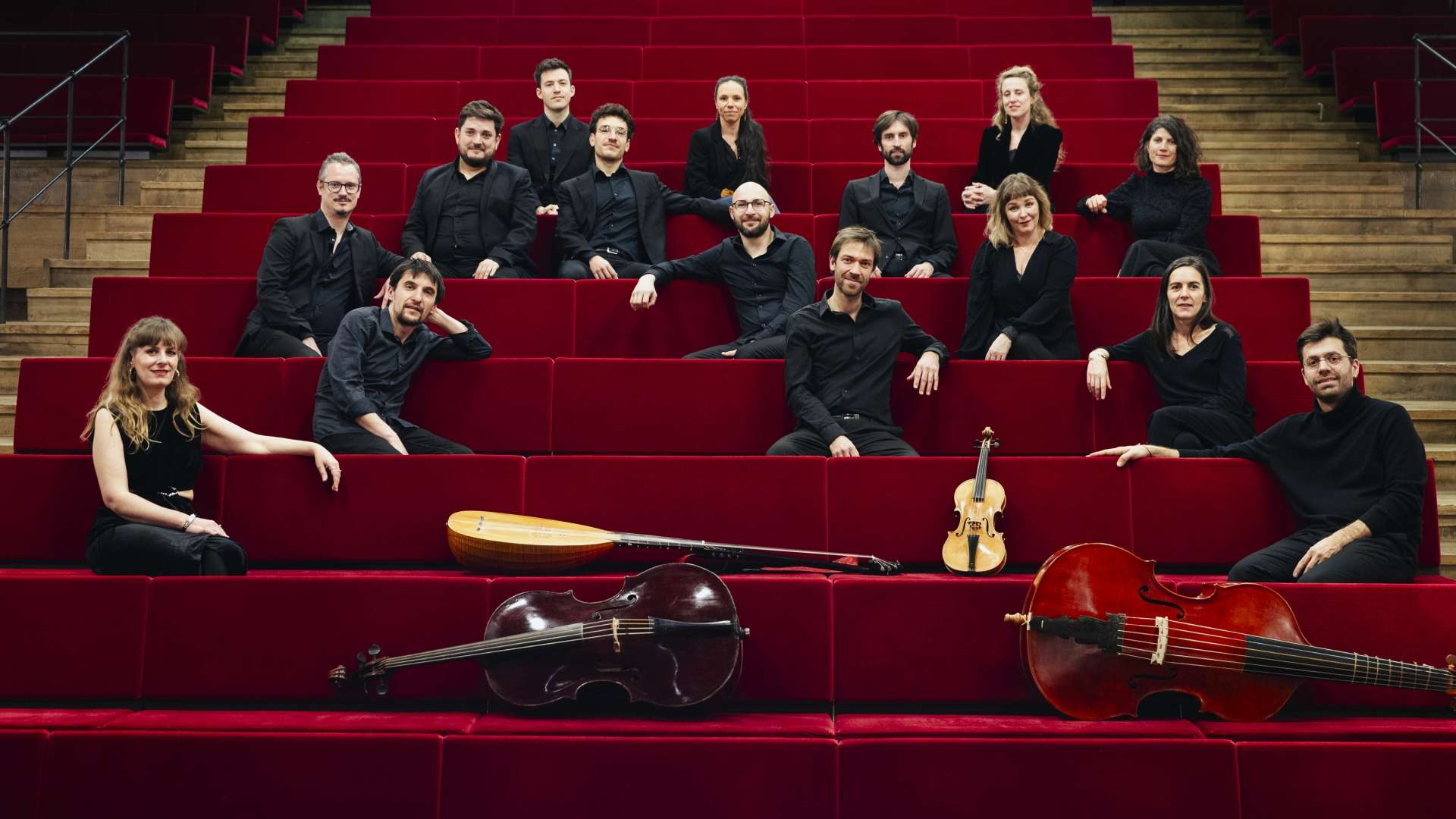 Dans une salle, l'ensemble est assis et regarde vers nous. Quelques instruments sont exposés.
