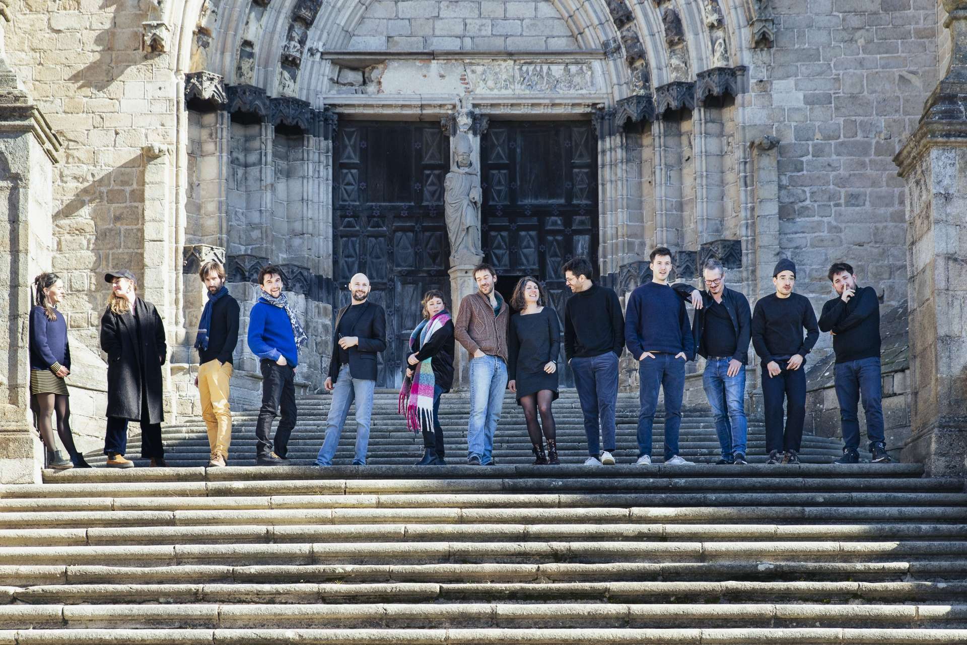 L'ensemble est debout en haut de marche et regarde vers nous. 