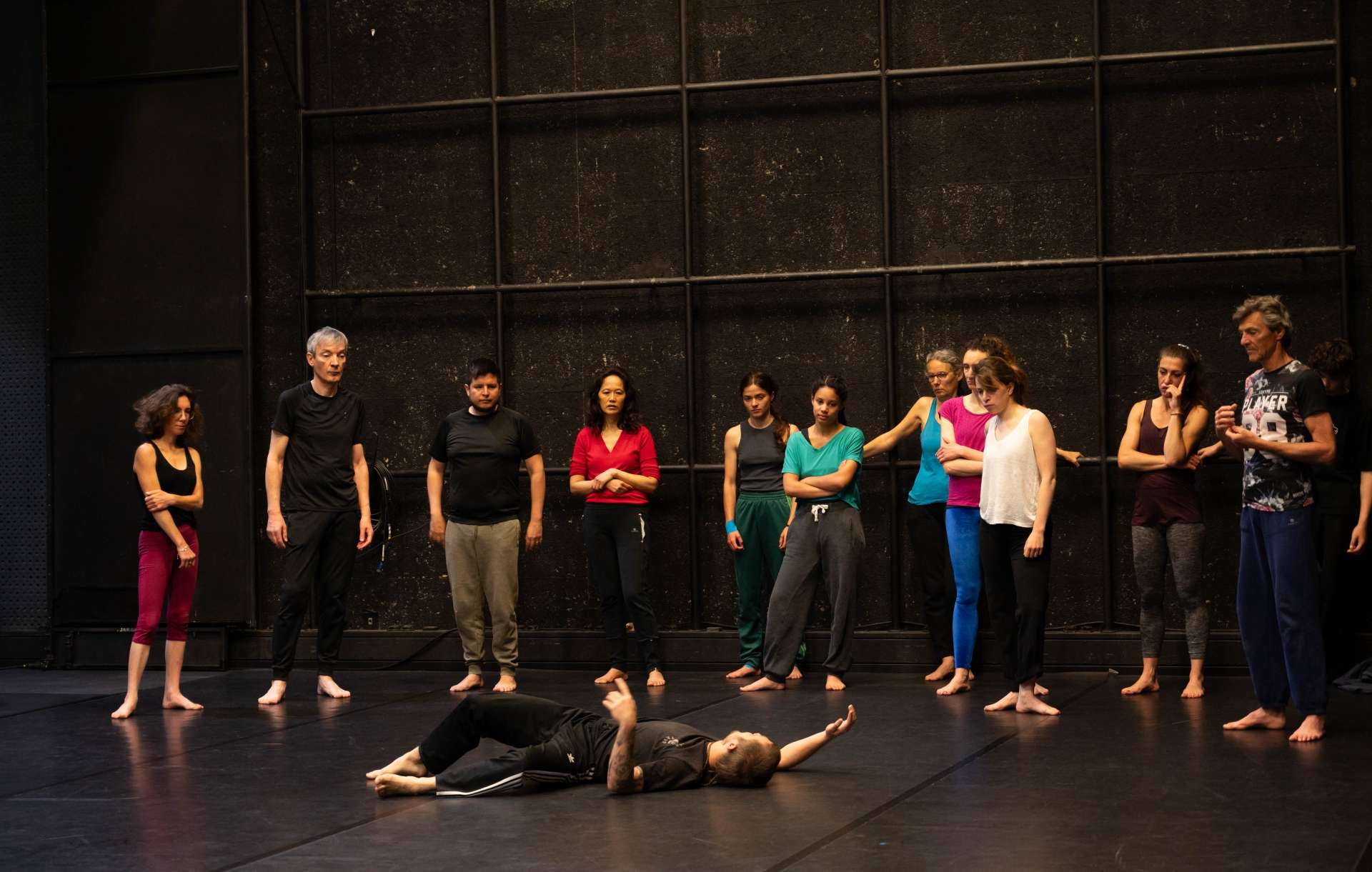 Photo de l'atelier de danse acrobatique, Clotaire montre un mouvement, les participant.es autour de lui le regarde.