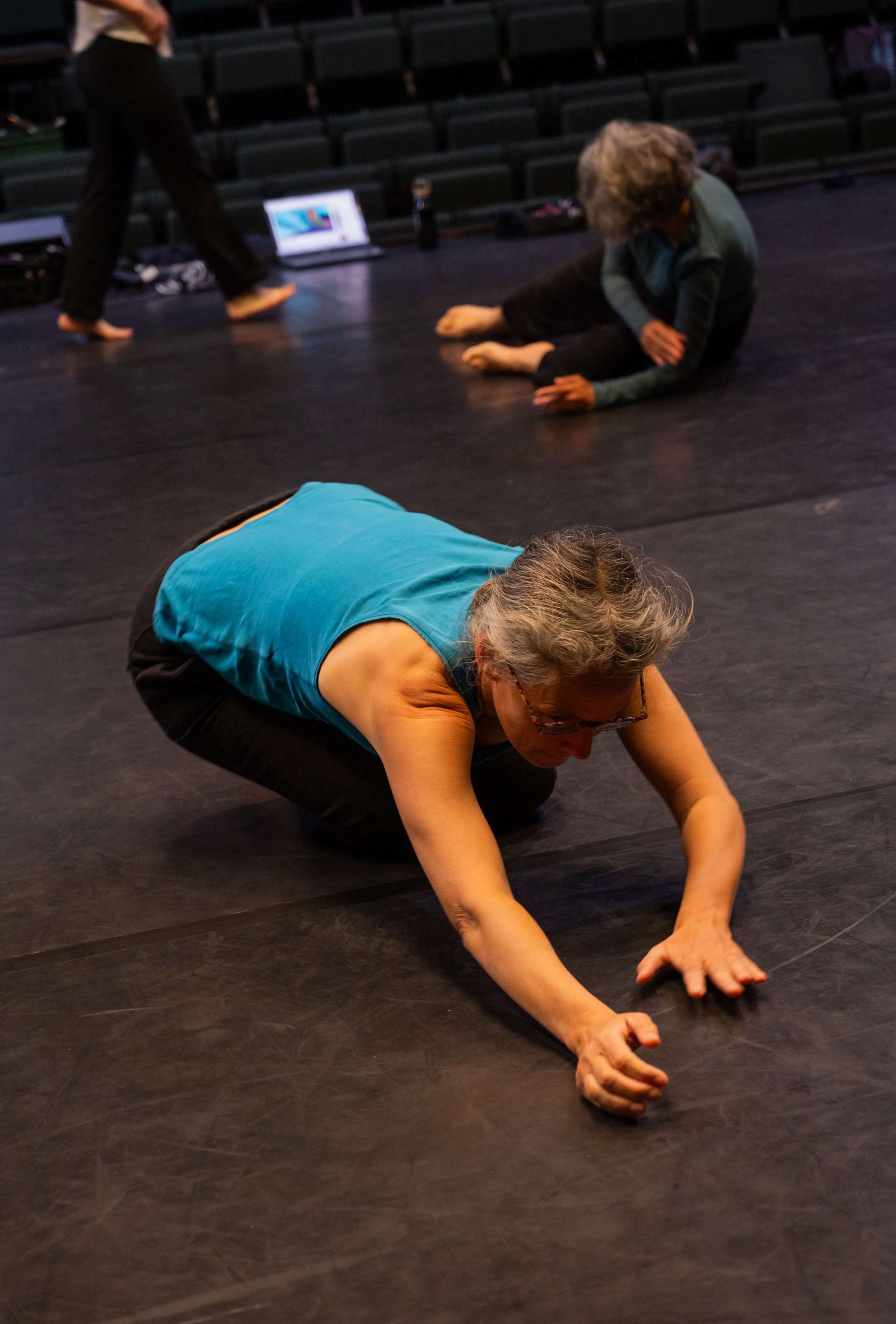 Photo de l'atelier de danse acrobatique, focus sur une participante accroupie sur le sol, les bras devant elle.