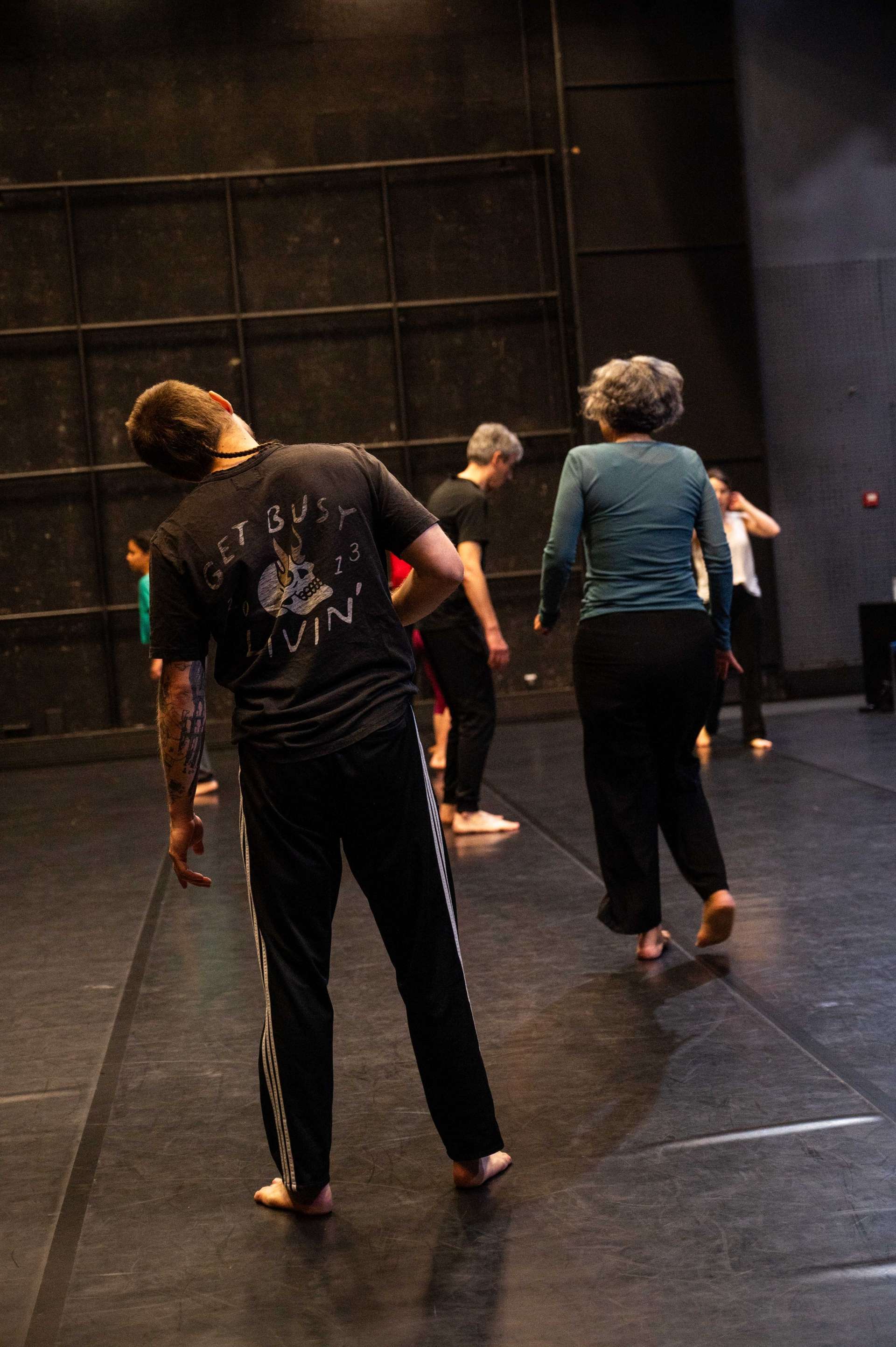 Photo de l'atelier de danse acrobatique, Clotaire en premier plan et quelques participant·es vu·es de dos en pleine marche dansante.