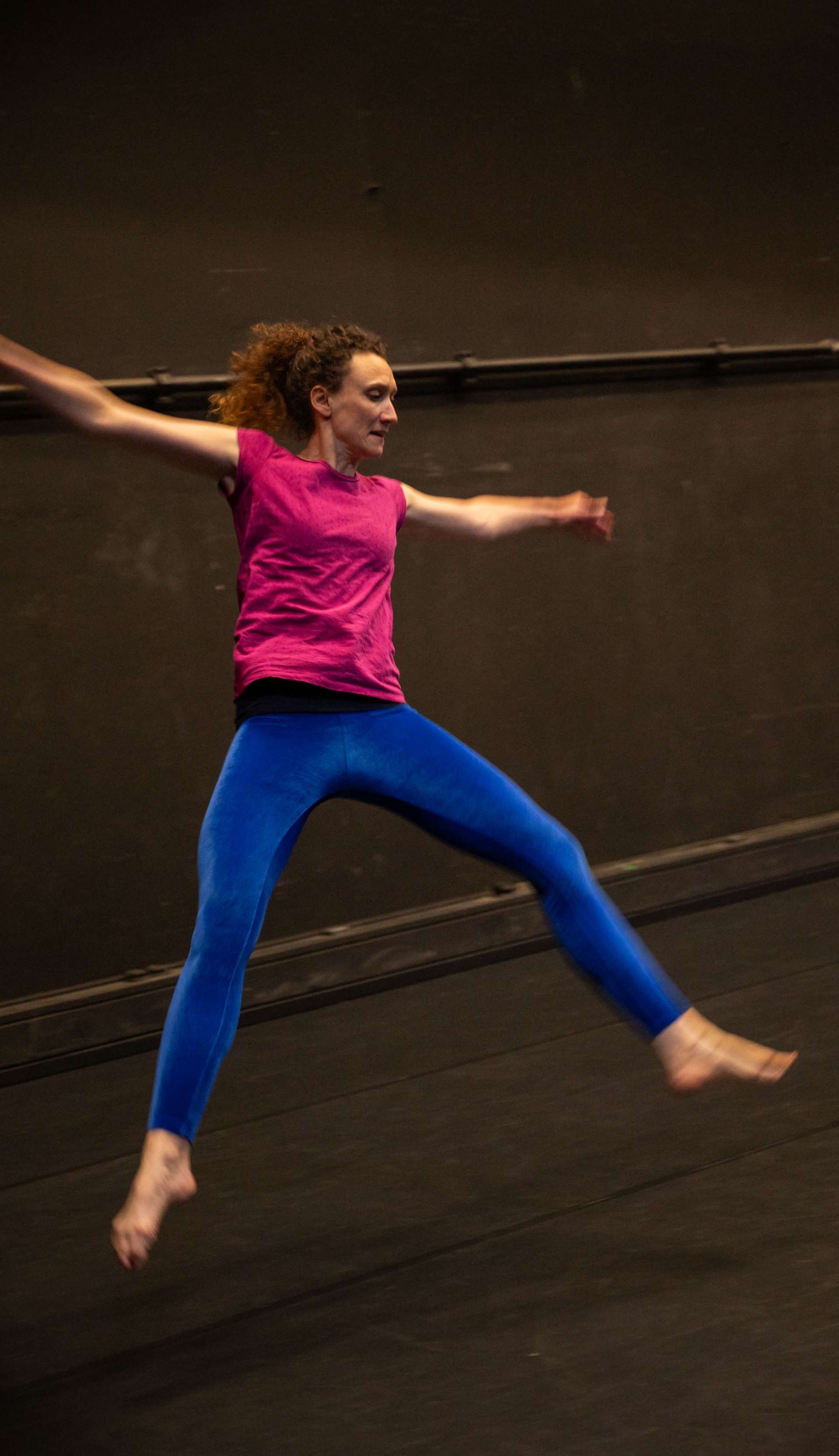 Photo de l'atelier de danse acrobatique, focus sur une participante en plein saut, les jambes et bras écartés.