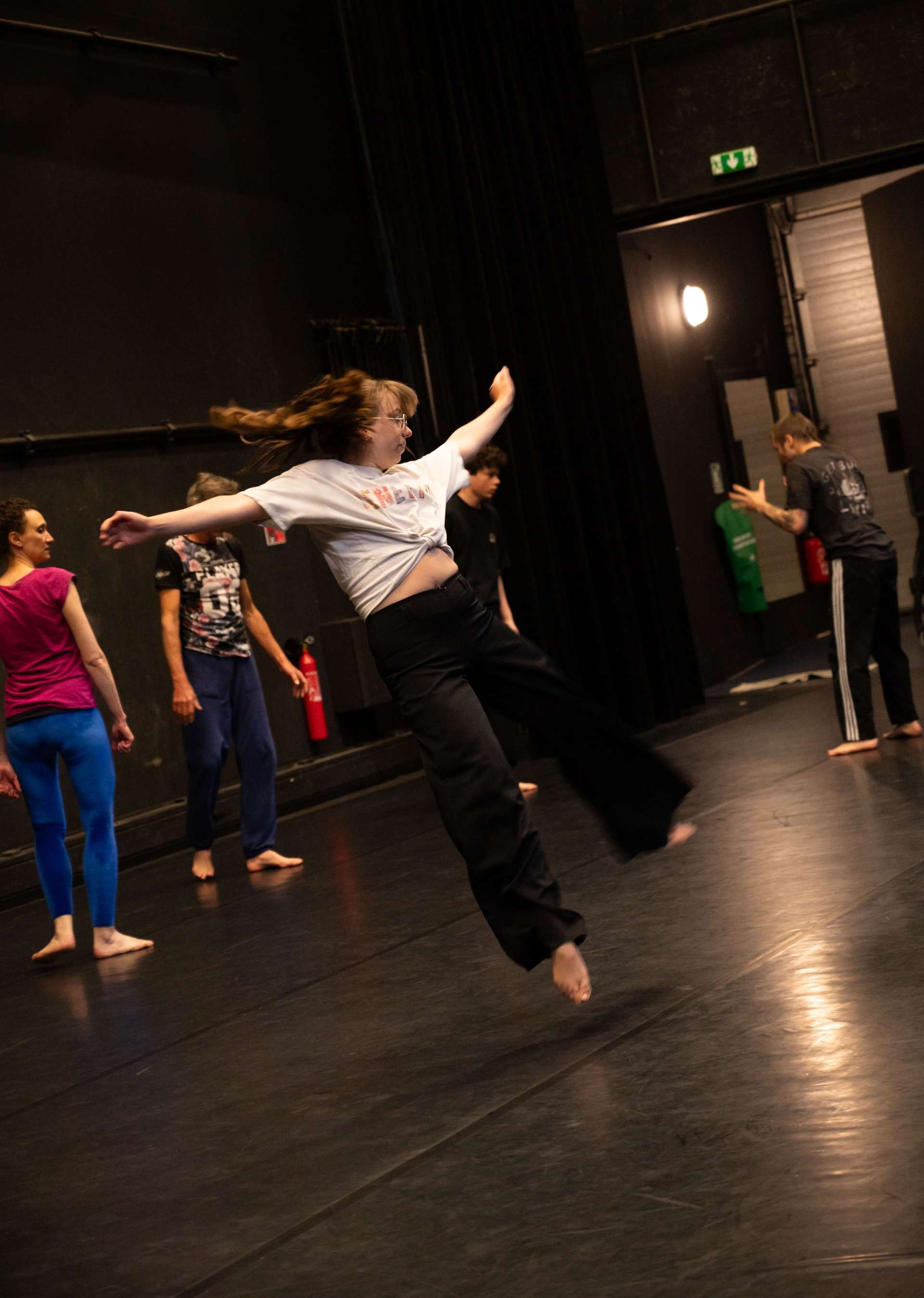 Photo de l'atelier de danse acrobatique, focus sur une participante en plein saut, les jambes et bras écartés.