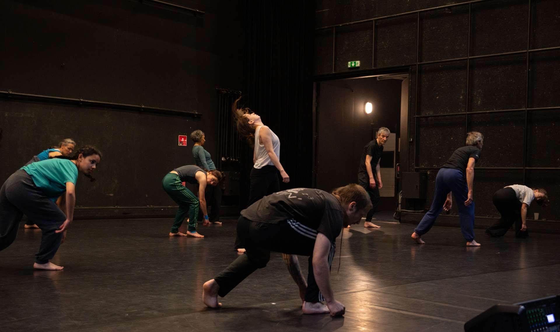 Photo de l'atelier de danse acrobatique, participants et participantes suivent les pas de Clotaire, accroupi pour un pas de danse.
