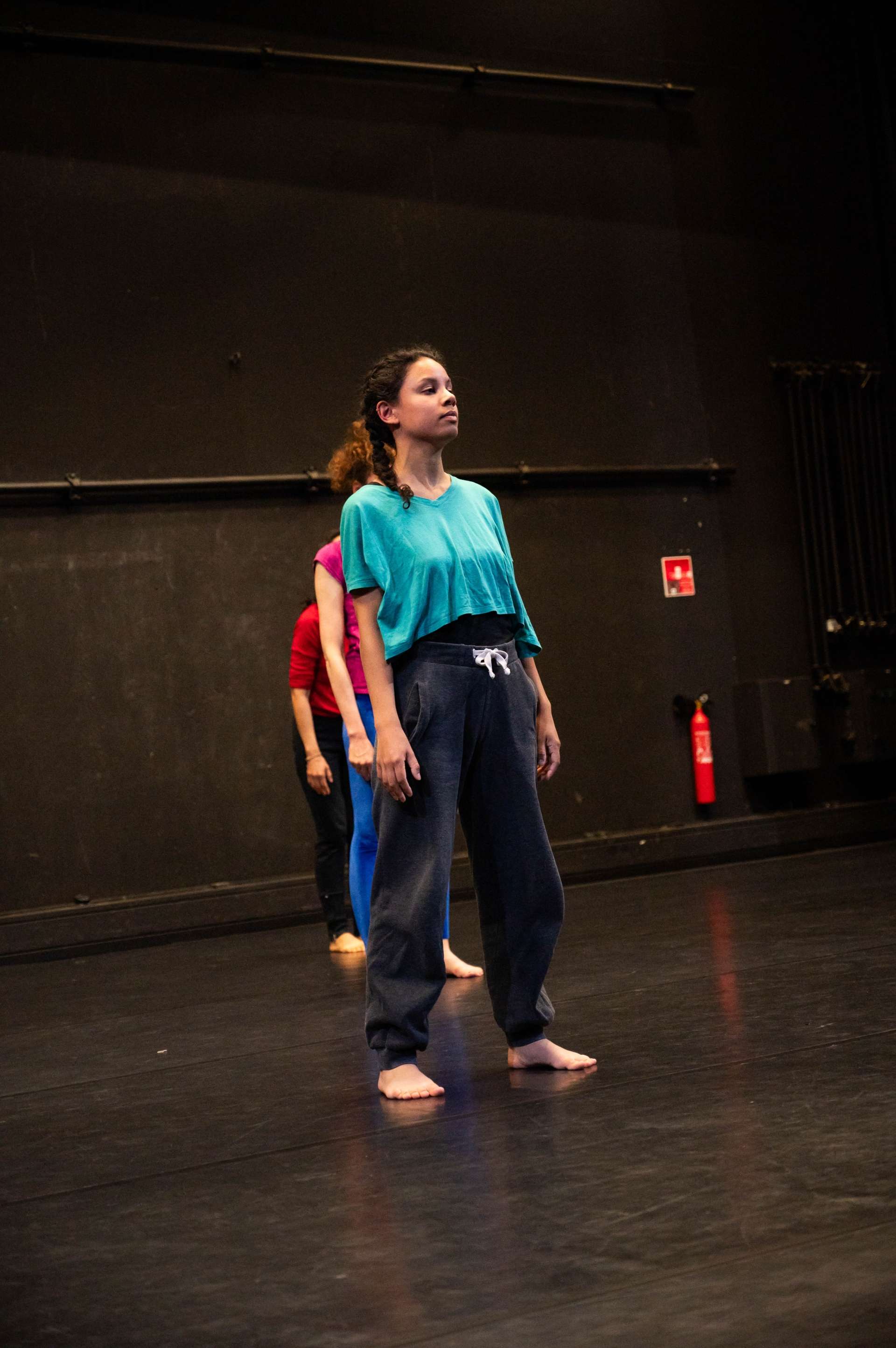 Photo de l'atelier de danse acrobatique, focus sur une participante, debout concentrée sur ce qu'il se passe devant elle. 
