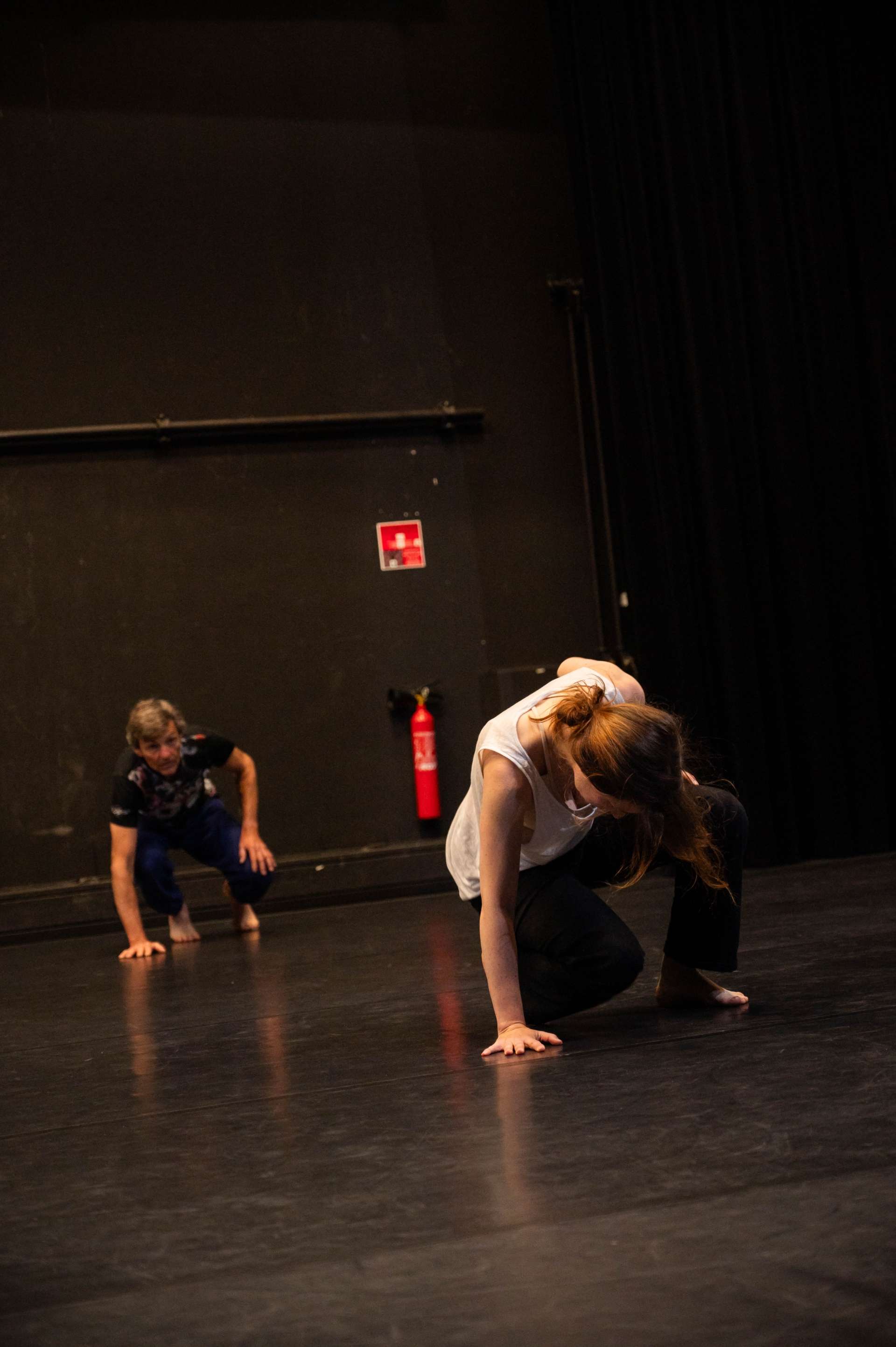 Photo de l'atelier de danse acrobatique, deux participant·es accroupi·es, une main sur le sol.