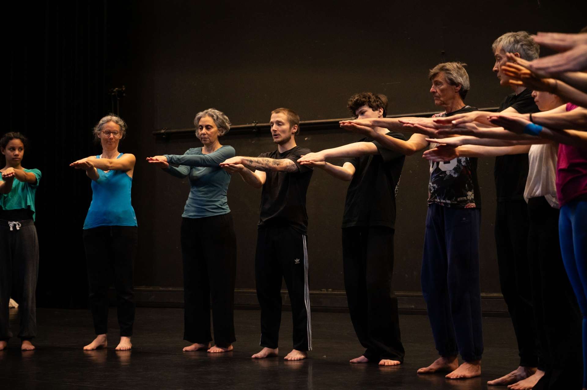 Photo de l'atelier de danse acrobatique, les participant·es aligné·es font des mouvement de danse avec leurs bras. 