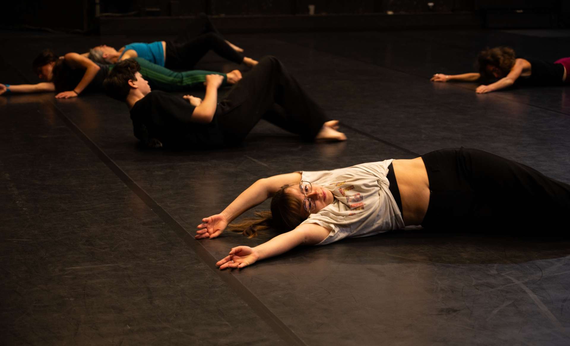 Photo de l'atelier de danse acrobatique, les participant·es allongé·es par terre et les bras en l'air.